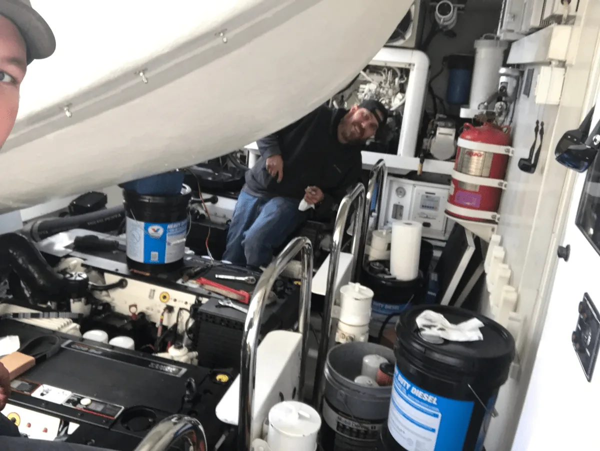 Marine mechanic working inside a boat engine bay