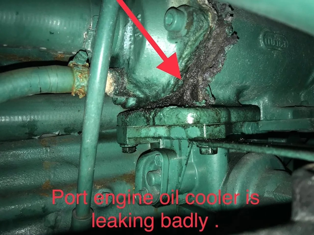 Survey finding photograph with a red callout arrow marking a badly leaking port engine oil cooler