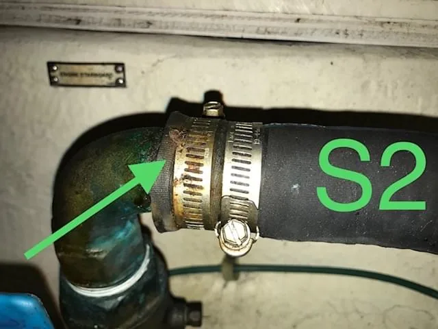 Survey finding photograph marked S2 with a green callout arrow pointing to a hose clamp on a cooling hose